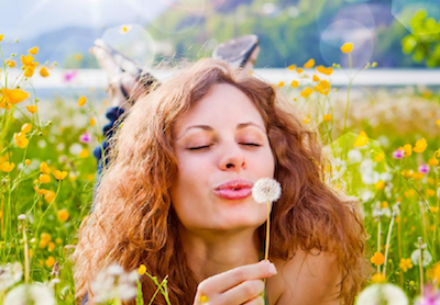 History of Allergy woman blowing dandelion