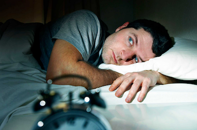 sleep symptoms man lying in bed can't sleep